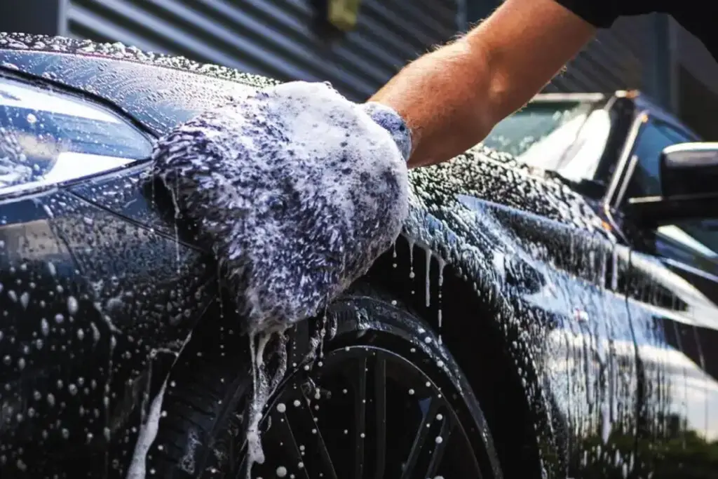 A soapy vehicle being washed with a wash mit.